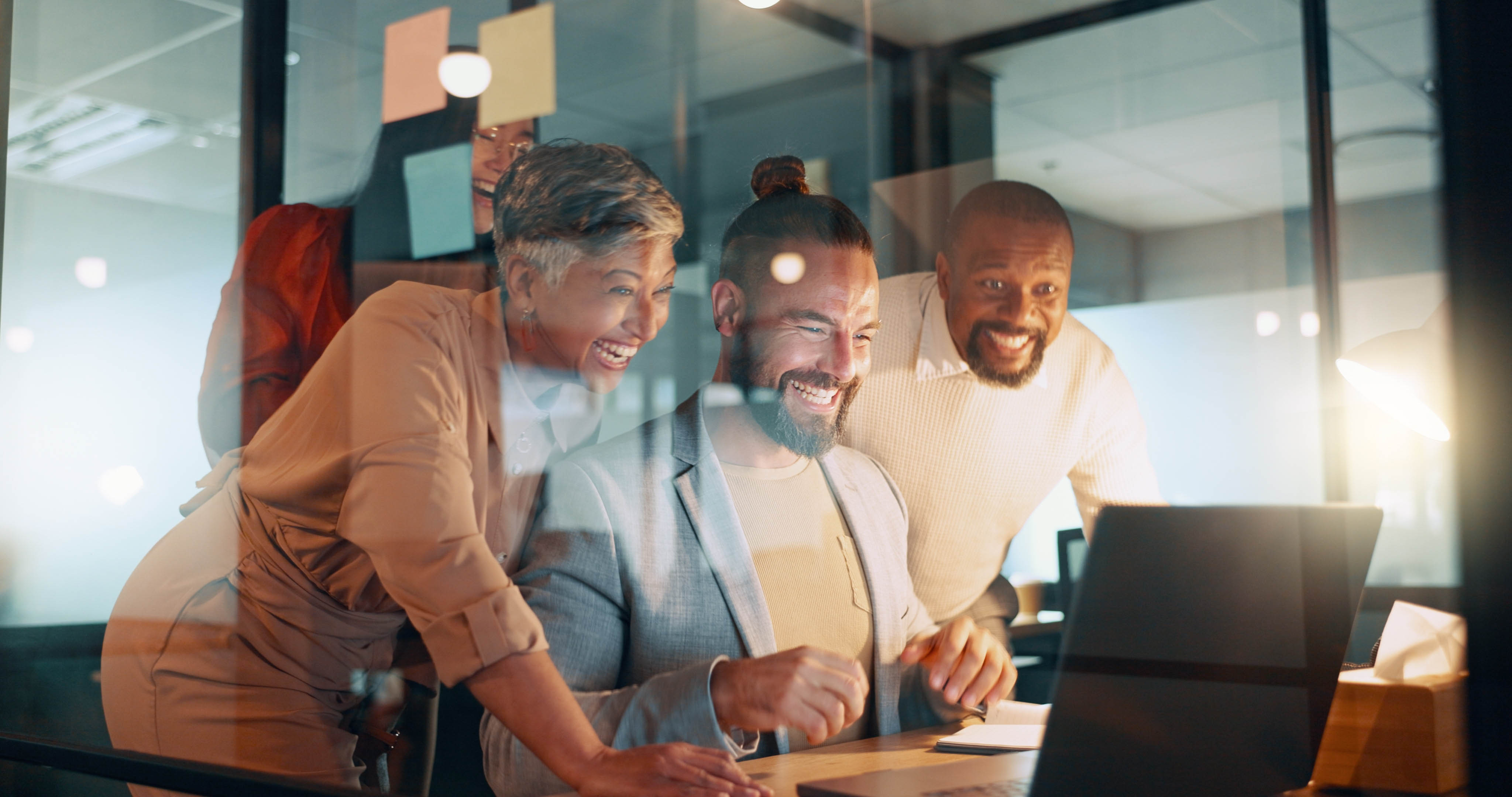 Diverse group of workmates sitting together in front of a computer laughing